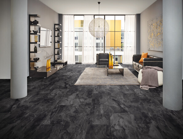 Moderner Wohnraum mit dunklem Vinylboden, großen Fenstern, schwarzem Sofa und dekorativen Elementen.