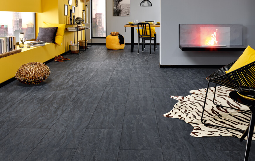 Stylish living room with dark laminate flooring from the series 'Ceramico', yellow accents, and a cosy fireplace.