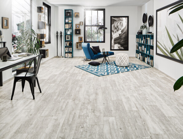 Bright room with stylish laminate flooring, featuring a desk, bookshelves, and a blue chair on a geometric rug.