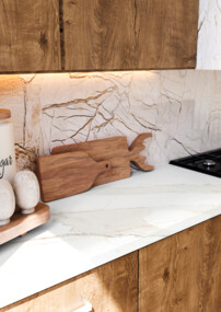 Moderne Küche mit Holzschränken, Gewürzbehältern und Gaskochfeld. Beleuchtung unter den Schränken hebt die Arbeitsplatte hervor.
