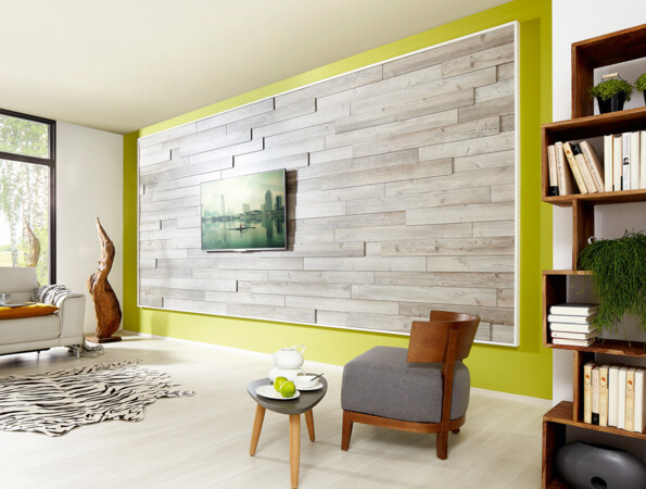 Modernes Wohnzimmer mit hellem Laminatboden, Akzentwand aus Holz, gemütlicher Sitzecke und Bücherregal.