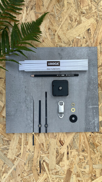 Werkzeuge und Zubehör für Laminatbodeninstallation auf Holzuntergrund, mit Pflanzen im Hintergrund.