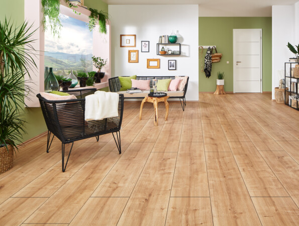 Ein gemütliches Wohnzimmer mit hellem Laminatboden, grünen Wänden und stilvollen Möbeln. Pflanzen und Dekorationen vervollständigen den Raum.
