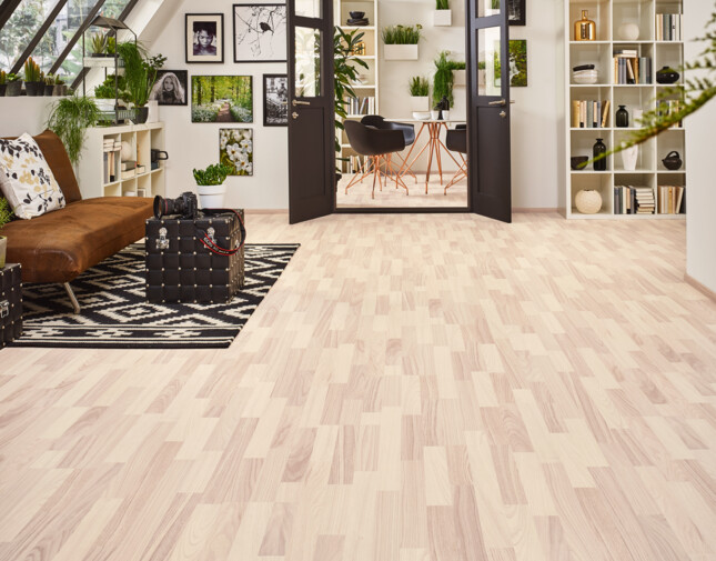 Bright room with light laminate flooring, large windows, and stylish decor; indoor plants and framed art add charm and warmth.