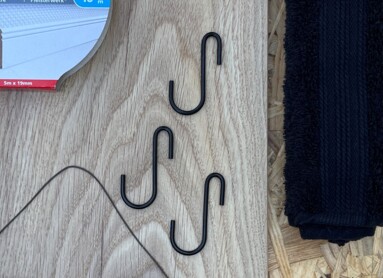 Verschiedene DIY-Materialien auf Holzplatte, darunter Tesa-Klebeband und Filztasche mit "Schnick Schnack"-Aufschrift.
