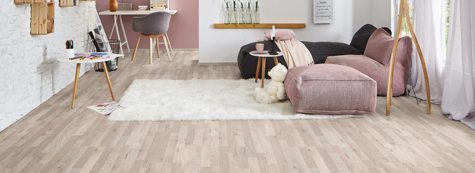 Living room with light laminate flooring, a cosy seating area, decorative shelves, and a work desk.