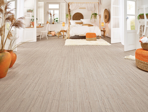 Helles Schlafzimmer mit Laminatboden der Serie 'Vinto', dekoriert mit Pflanzen, orangen Akzenten und einem gemütlichen Bett.