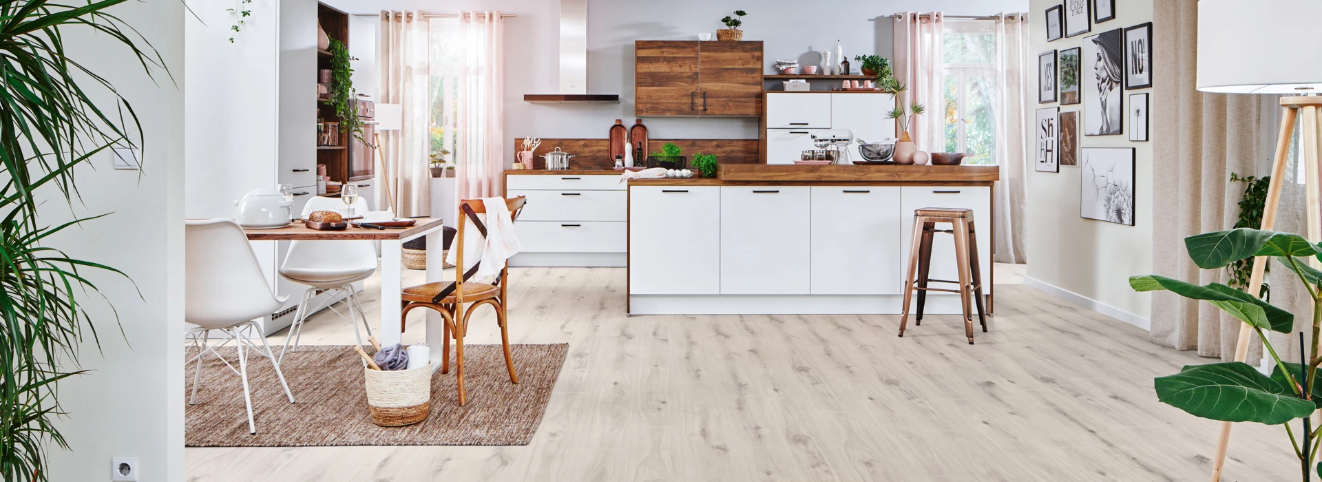 Spacious kitchen with laminate flooring, white cabinets, wooden countertops, and dining area with chairs.
