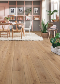 Wohnzimmer mit Laminatboden, weißen Möbeln, Pflanzen und einem Esstisch auf einem flauschigen Teppich.