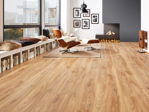 Modernes Wohnzimmer mit hellem Laminatboden, stilvollen Möbeln und großen Fenstern. Gemütliche Sitzbank mit Kissen und Bücherregalen darunter.