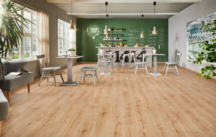 Cozy café interior with light laminate flooring, green accent wall, and simple furniture.