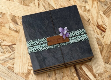 Ein stilvoll verpacktes Geschenk mit feinem Band und Blume auf strukturiertem Laminatboden.