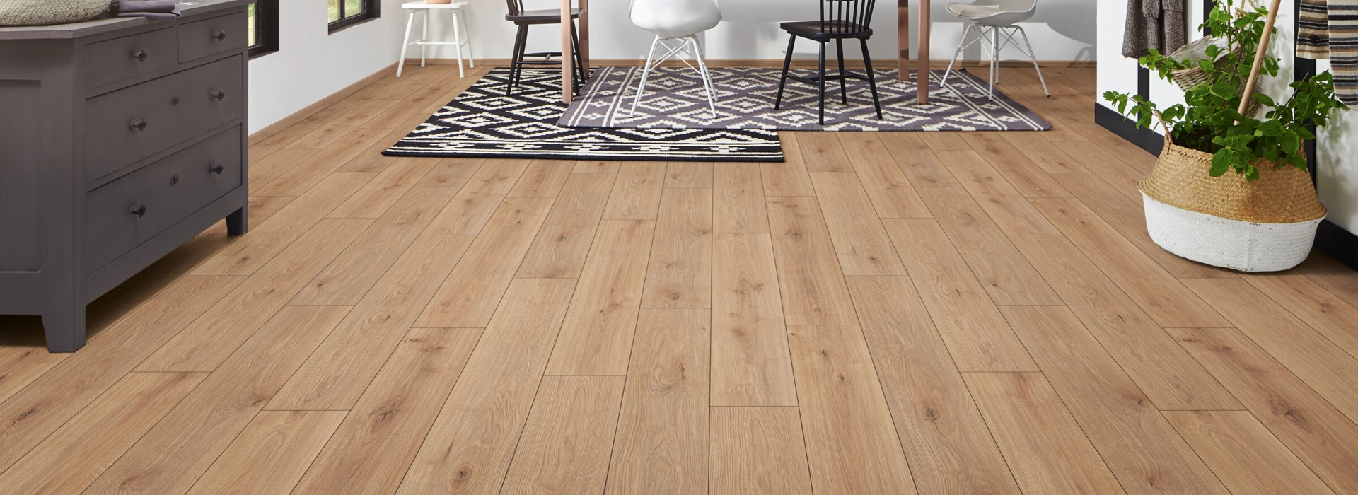 Laminate flooring in a bright dining area with plants, brick wall, and mixed chairs.