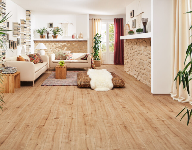 Living room with laminate flooring, cosy sofas, potted plants, and a stone accent wall.