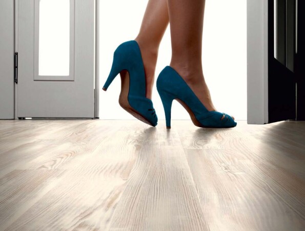 Frau in blauen High Heels auf Laminatboden in einem hellen Raum.