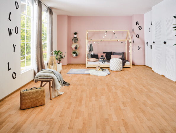 Helles Zimmer mit Laminatboden der Serie 'Family', einem Bett mit Rahmen, weichen Kissen und dekorativen Lichtern, großen Fenstern und Pflanzen.