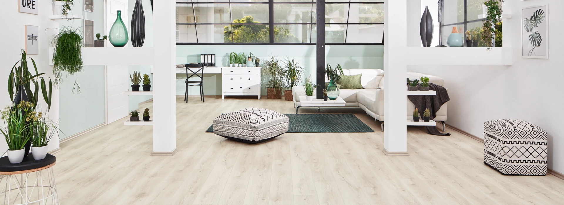 Bright living room with light laminate flooring from the series 'Vinto', greenery, and contemporary furniture.