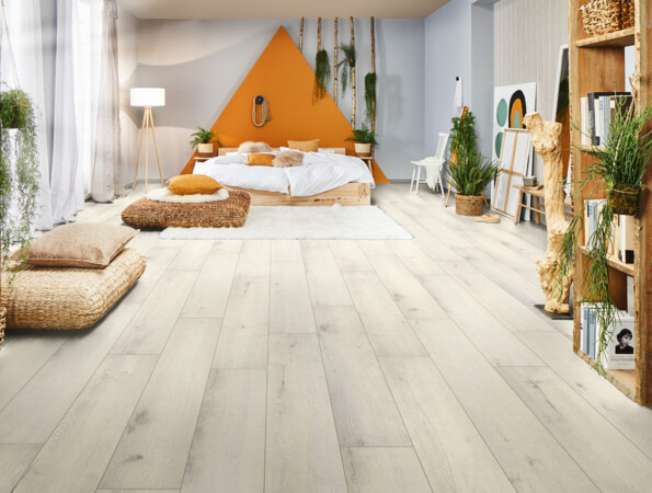 Modernes Schlafzimmer mit hellem Laminatboden, gemütlichem Bett, Pflanzen und Regalen, die eine einladende Atmosphäre schaffen.