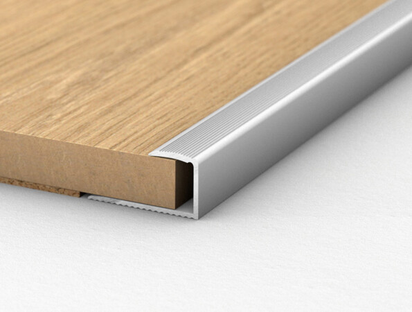 Close-up of laminate flooring edge with aluminium profile on a white background.