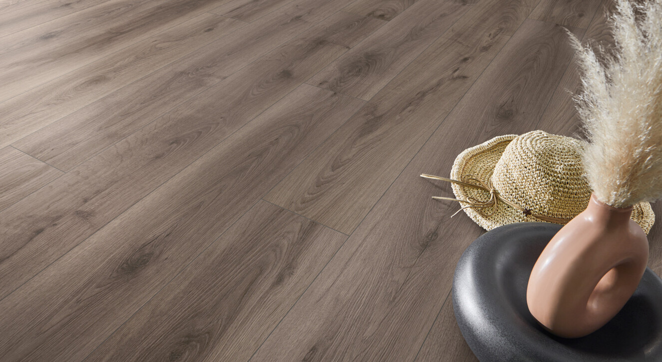 Laminate flooring in a natural wood finish with a decorative vase and straw hat placed on the surface.