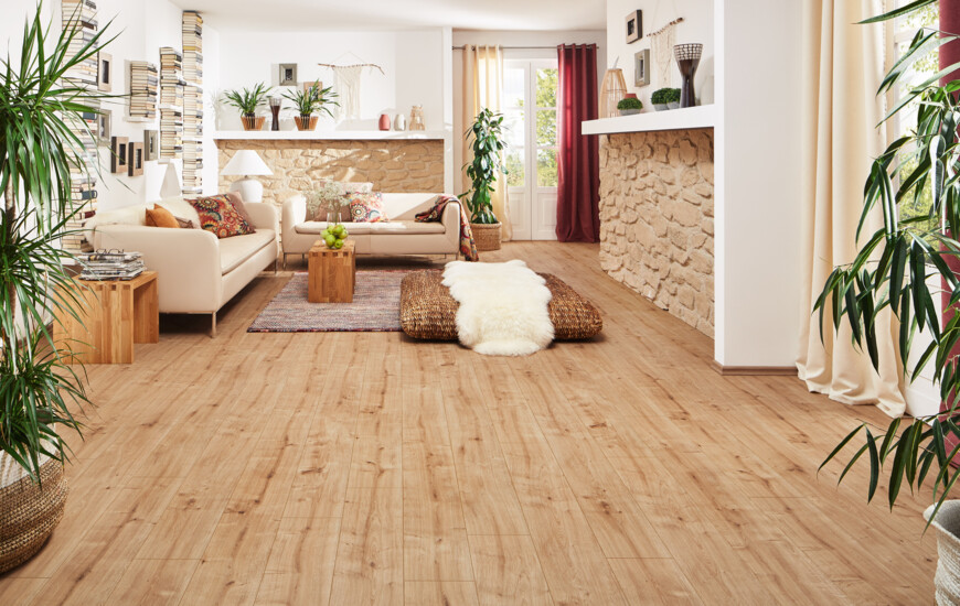 Living room with laminate flooring, cosy sofas, potted plants, and a stone accent wall.