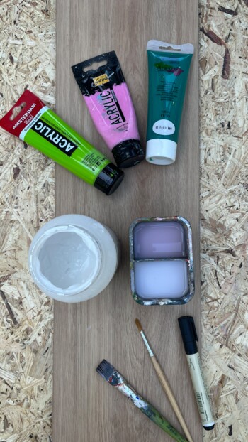 Acrylfarben, Pinsel und Marker auf Laminatboden.