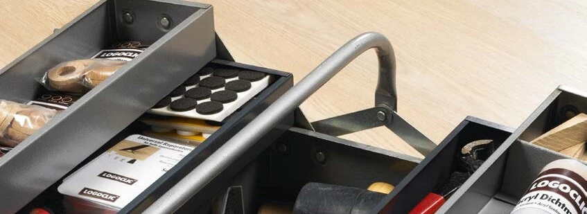 Werkzeugkasten mit Zubehör zur Verlegung von Laminatboden auf hellem Boden.