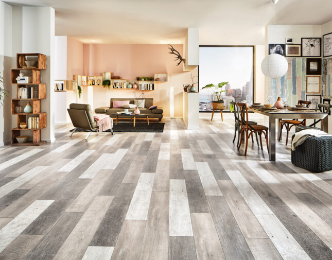 Geräumiges Wohnzimmer mit Laminatboden, moderner Einrichtung, inklusive Bücherregal, Ledersesseln und Essbereich mit Tisch und Stühlen.