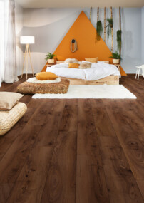 Gemütliches Schlafzimmer mit dunklem Laminatboden, weißen Möbeln und Pflanzenakzenten.