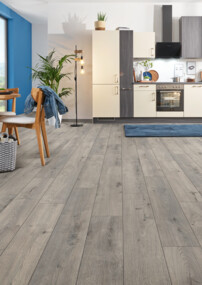 Moderne Küche mit blauem Akzent, Feuchtraumboden der Serie 'Aquaprotect smart' und Essbereich mit Holzmöbeln, großen Fenstern und Pflanzen.