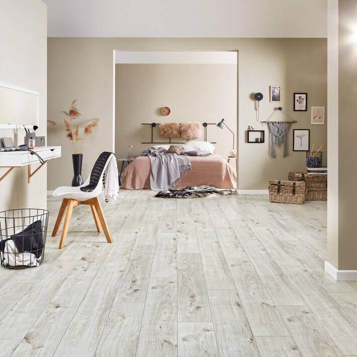 Ein Schlafzimmer mit beigen Wänden und hellem Laminatboden