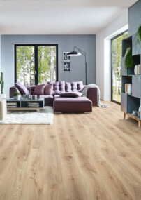 Modernes Wohnzimmer mit hellen Laminatboden, lila Sofa, Kamin, und großen Fenstern mit Blick ins Grüne. Pflanzen und Regale ergänzen das Ambiente.
