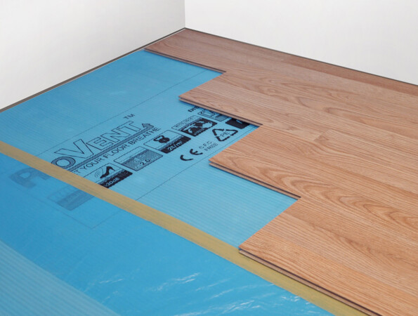 Verlegung von Laminatboden mit blauer Unterlage an einer weißen Wand.
