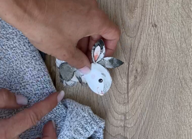 Person arrangiert tierische Aufkleber auf Laminatdiele, neben Kleiderbügeln.