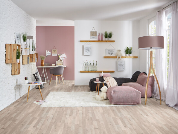 Living room with light laminate flooring, a cosy seating area, decorative shelves, and a work desk.