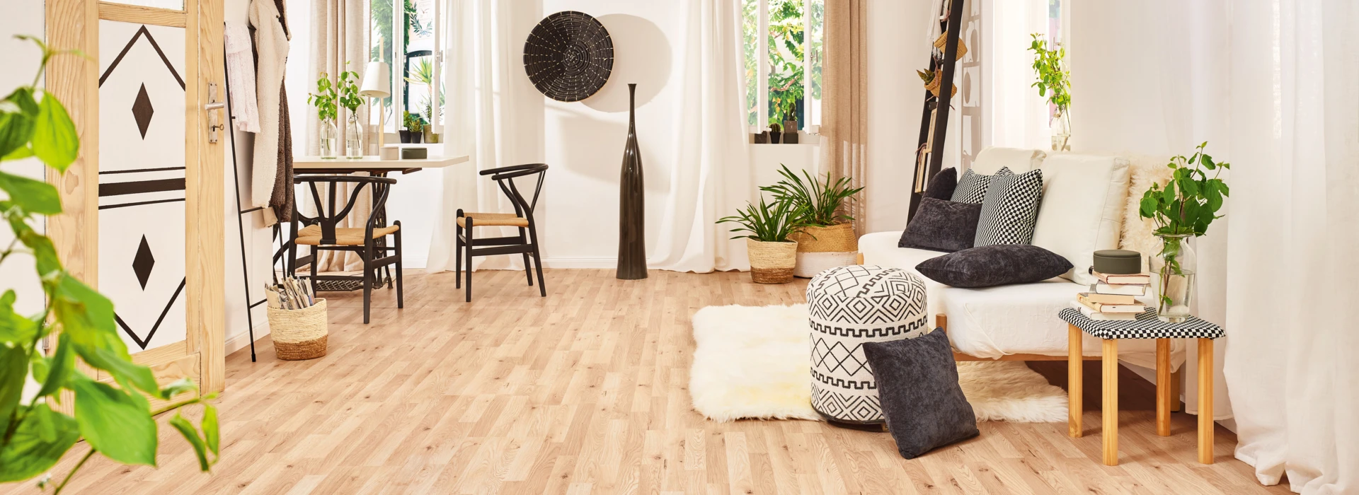 Living room with light laminate flooring, cosy seating, and green plants.
