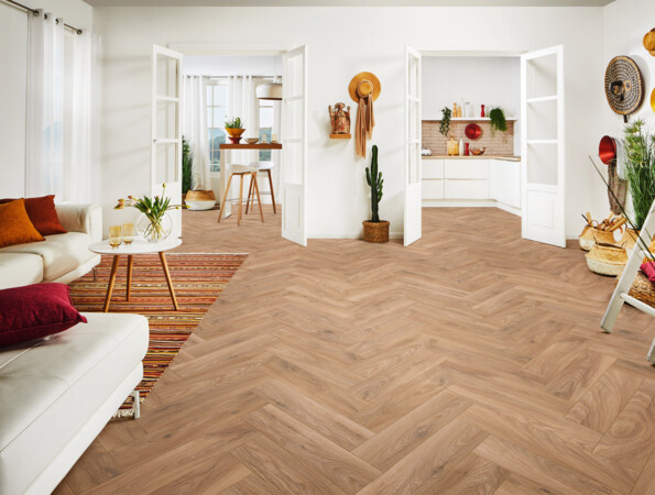Bright living space with herringbone laminate flooring, white furniture, and decorative plants.