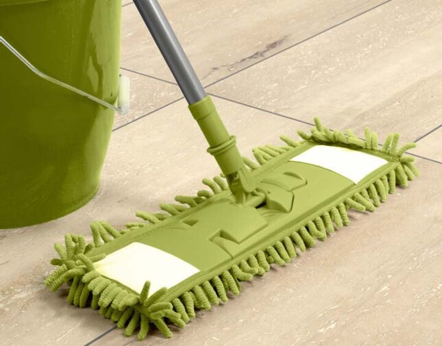 Grüner Mopp und Eimer auf Laminatboden.