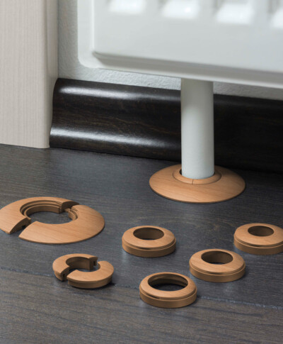 Zubehörteile aus Holz für Laminatboden zur Rohrabdeckung, neben einem Heizkörper montiert.
