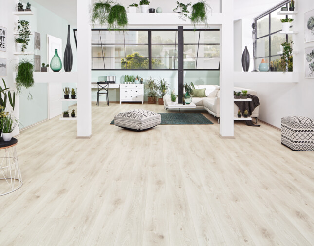 Bright living room with light laminate flooring from the series 'Vinto', greenery, and contemporary furniture.
