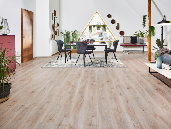 Living room with grey chairs, a sofa, and plants. Light laminate flooring from the series 'Vinto' enhances the bright, airy atmosphere.