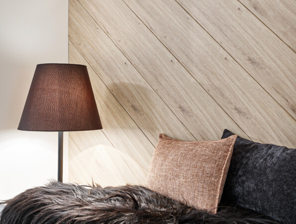 Cosy corner with a lamp, textured cushions, and a black fur throw, featuring wall panels in the background.