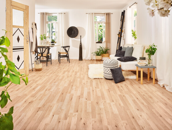 Living room with light laminate flooring, cosy seating, and green plants.