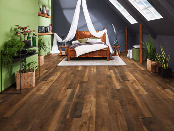 Spacious attic bedroom with elegant laminate flooring, featuring a canopy bed, skylights, and lush green plants.