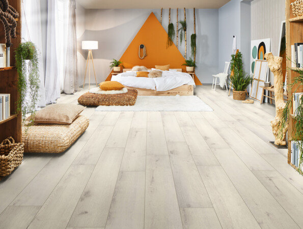 Schlafzimmer mit hellem Laminatboden, gemütlichem Bett und Pflanzen.