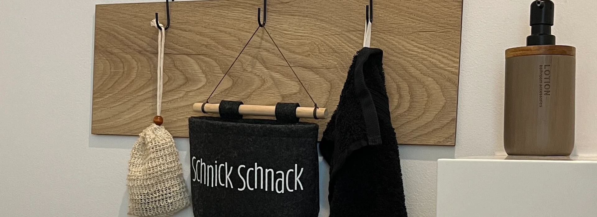 Spiegel über Wandhaken mit Tasche und Handtuch, Pflanze im Vordergrund.
