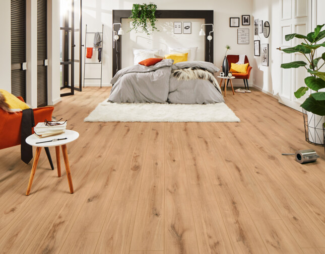 Bedroom with light laminate flooring, cosy bed, and vibrant decor, showcasing stylish interior design.
