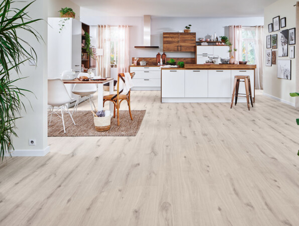 Spacious kitchen with laminate flooring, white cabinets, wooden countertops, and dining area with chairs.