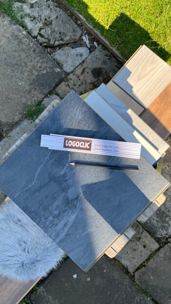 Eine Auswahl an Laminatboden-Mustern von LOGOCLIC<sup>®</sup> auf einem Tisch im Freien.