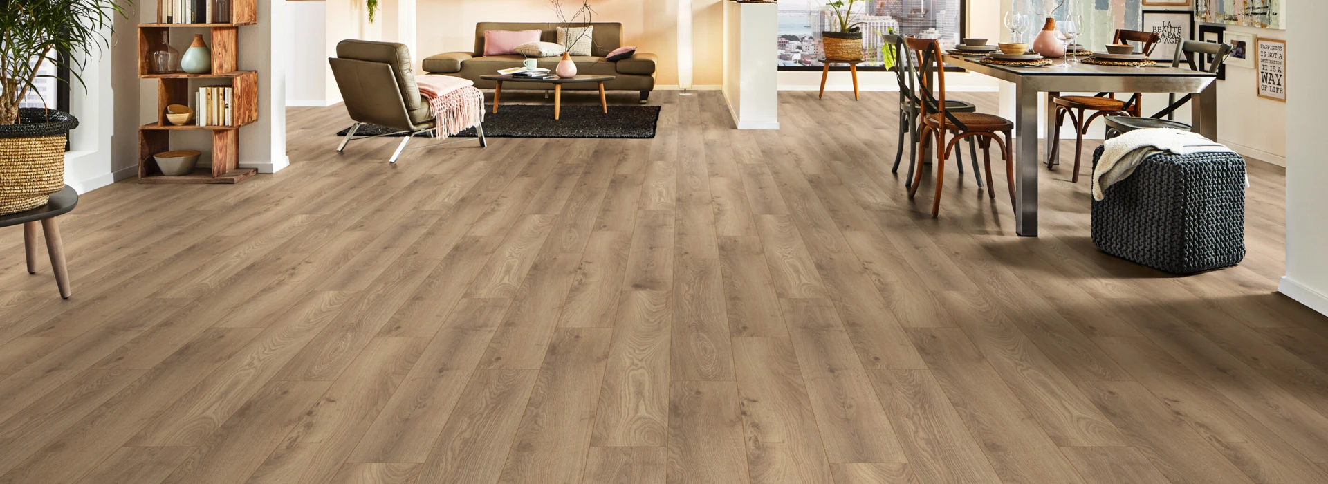 Ein modern eingerichtetes Wohnzimmer mit hellem Laminatboden der Serie 'Aquaprotect Smart Silent', Regalen, Esstisch und Pflanzen.